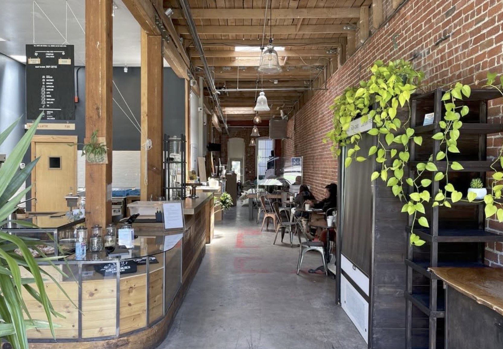The exposed brick and timber interior hallway at Sextant Coffee Roasters, with the counter and seating